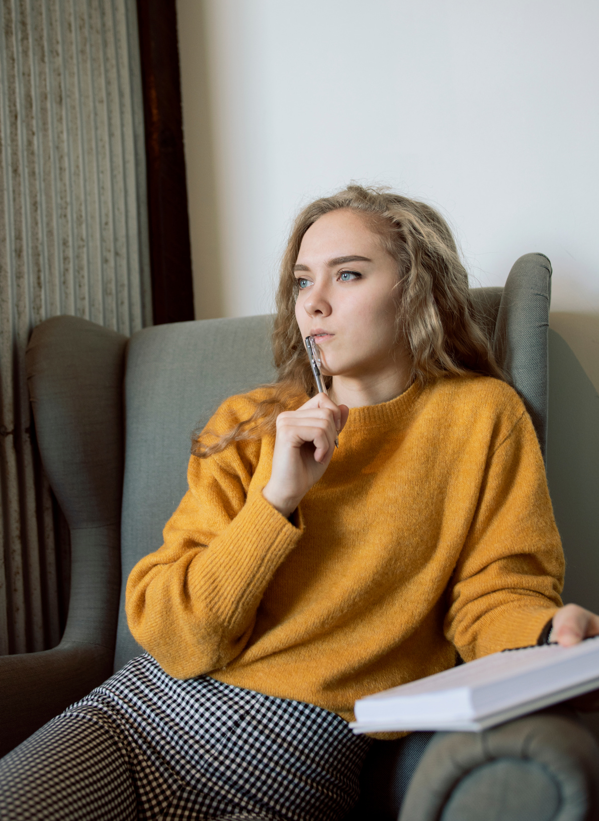Woman in Yellow Jacket Thinking While Holding a Pen and Notebook
